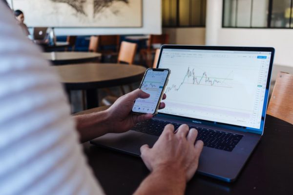 Stock Trading - person using smartphone and MacBook Pro