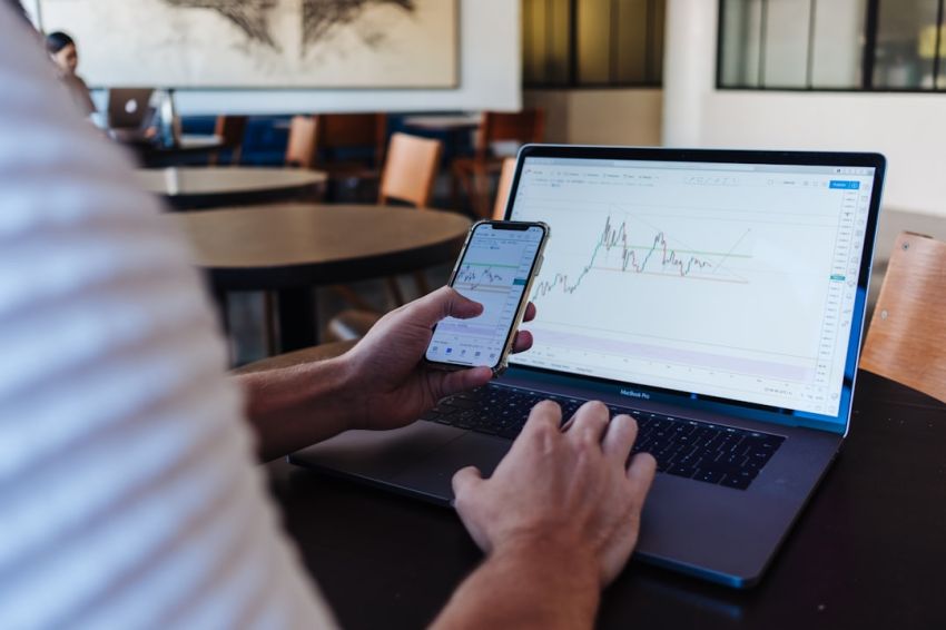 Stock Trading - person using smartphone and MacBook Pro