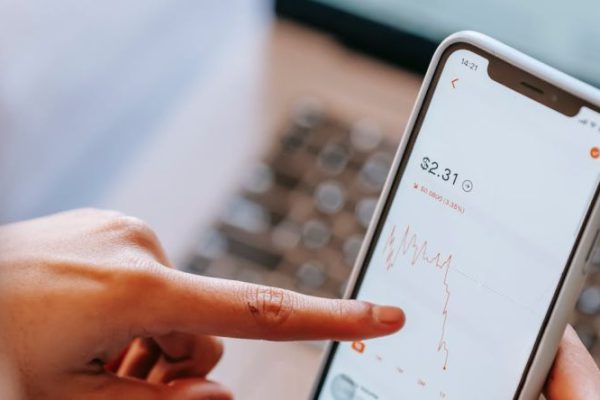 Stock Trading - Crop dealer analyzing graphic while using application on smartphone screen