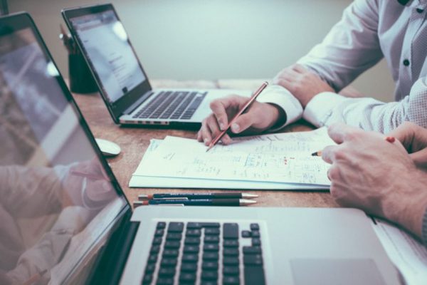 Tech Stocks - person holding pencil near laptop computer