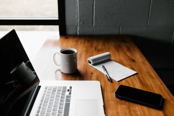 Tech Stocks - MacBook Pro, white ceramic mug,and black smartphone on table