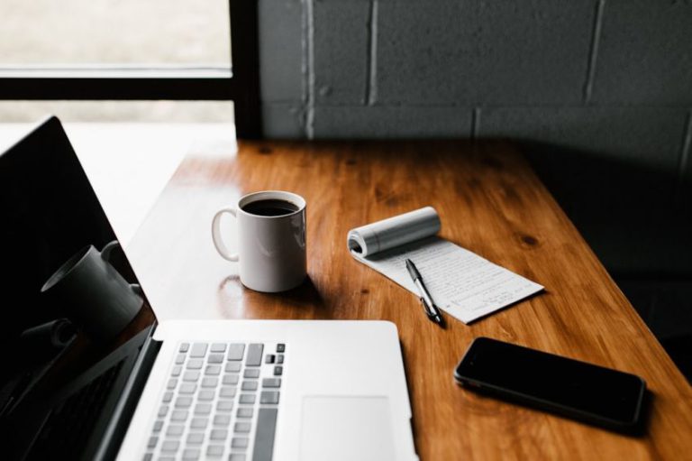 Tech Stocks - MacBook Pro, white ceramic mug,and black smartphone on table