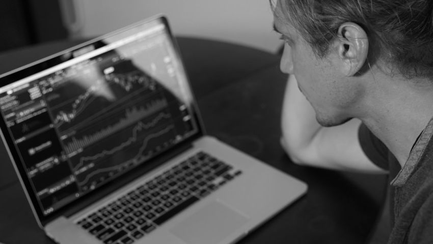 Stock Trading - grayscale photo of man looking at macbook pro