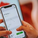 Stock Trading - Crop dealer touching screen on smartphone with trading application