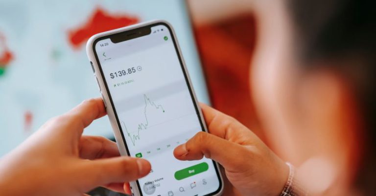 Stock Trading - Crop dealer touching screen on smartphone with trading application