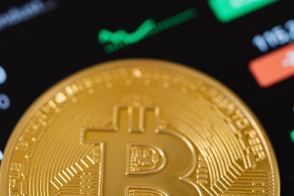 Stock Trading - Gold Bitcoin Coin Lying on a Phone Displaying Cryptocurrency Graphs