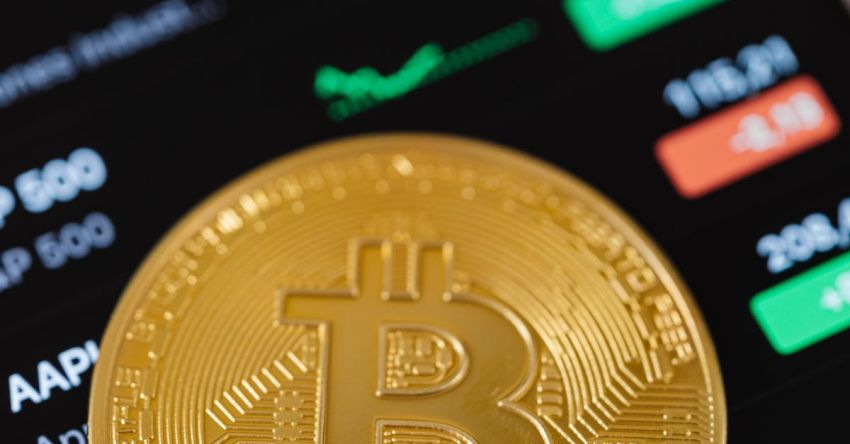 Stock Trading - Gold Bitcoin Coin Lying on a Phone Displaying Cryptocurrency Graphs