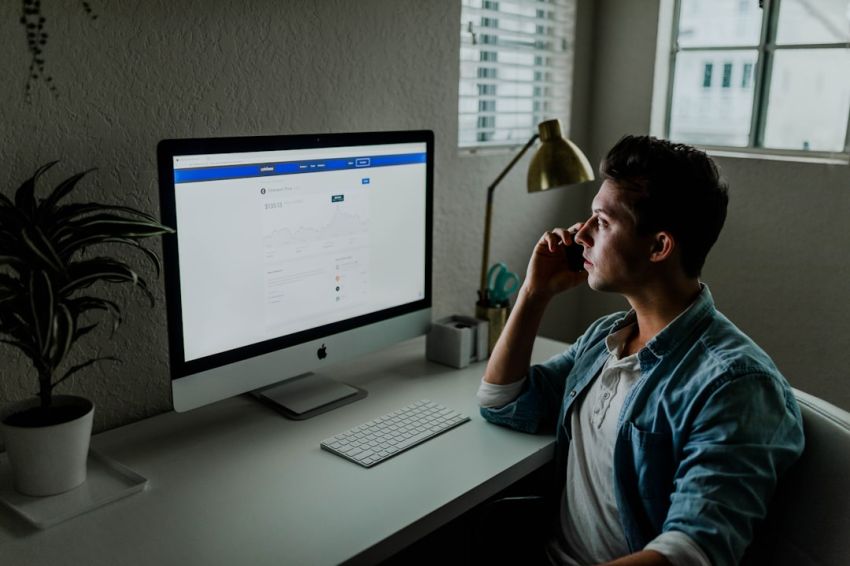 Stock Trading - man in blue denim jacket facing turned on monitor