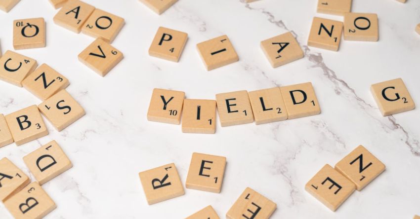 Dividend - Scrabble letters spelling yield on a white table
