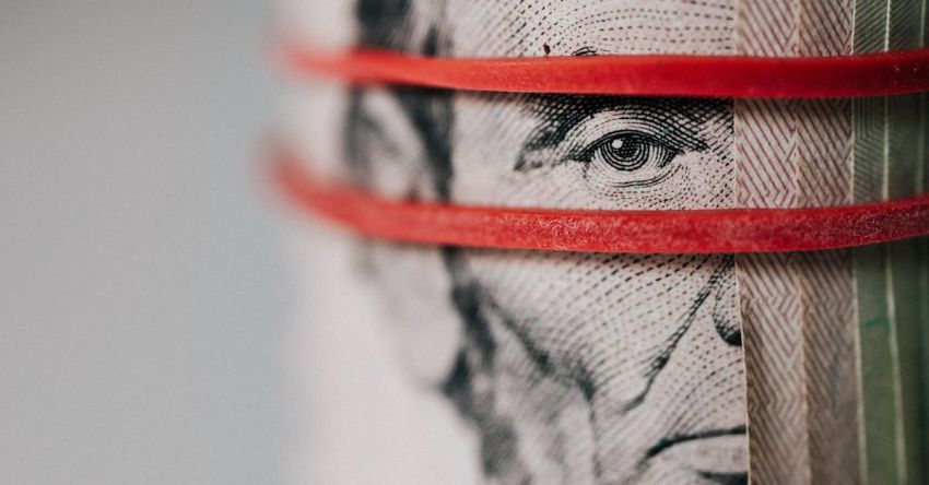 Economies - Closeup of rolled United States five dollar bills tightened with red rubber band