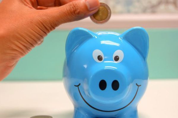 Index Funds - Person Putting Coin in a Piggy Bank