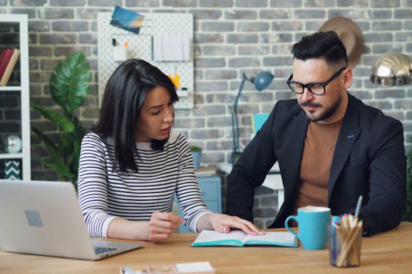 Agreements - A man and woman sitting at a desk with a laptop