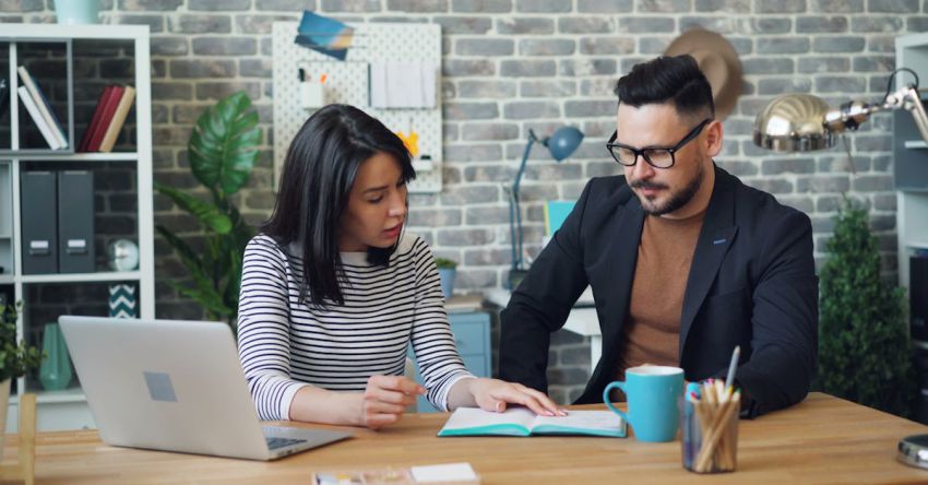 Agreements - A man and woman sitting at a desk with a laptop