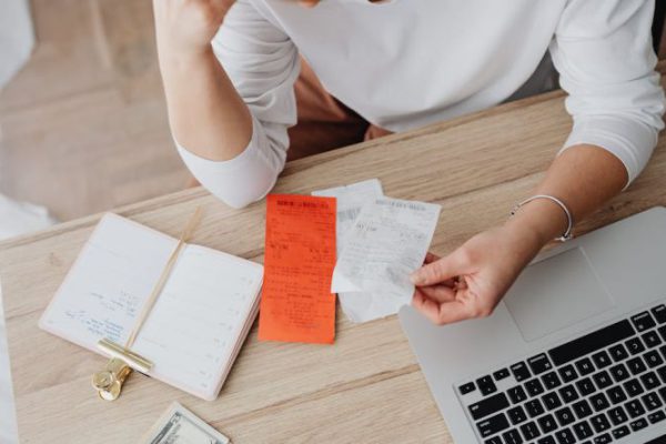 Inflation - Woman Sitting Behind the Desk and Looking at Receipts 