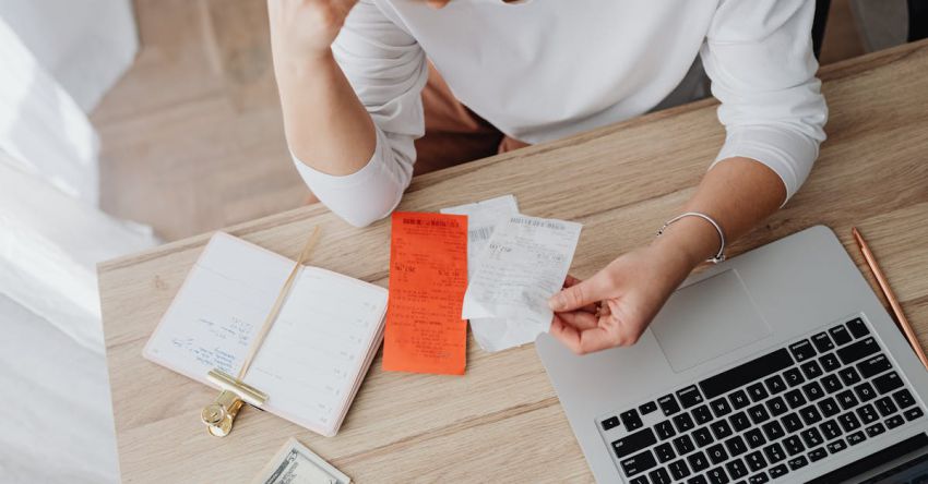 Inflation - Woman Sitting Behind the Desk and Looking at Receipts 